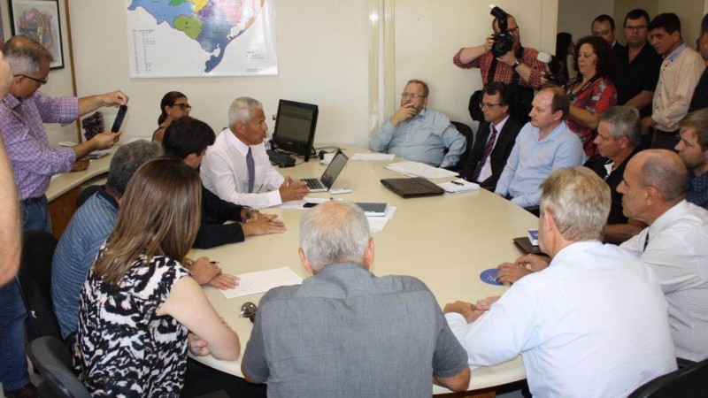 Secretário Gabbardo está entre os participantes da reunião. Alguns estão sentados em torno de uma mesa redonda e outros estão de pé.