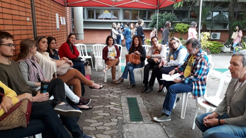 Participantes do evento conversam sentados, ao ar livre.