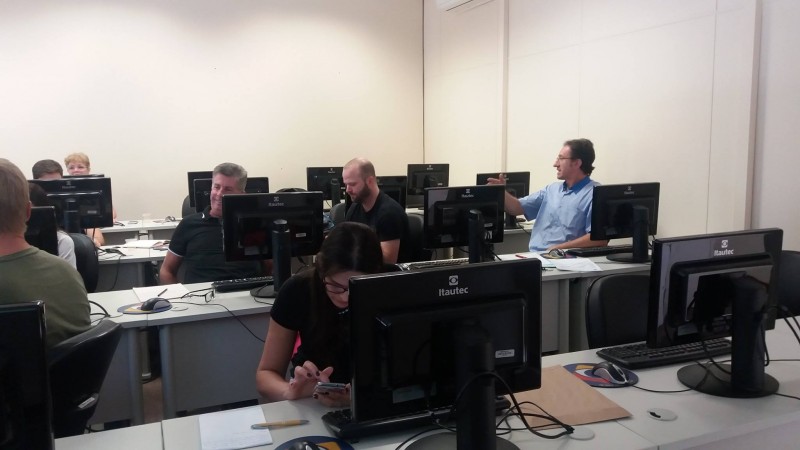 Técnicos, sentados, trabalham em seus computadores.