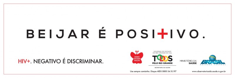 Imagem com texto: Beijar é positivo (o T é uma cruz). HIV+ (positivo). Negativo é discriminar. A imagem contém os logos #zerodiscriminação, Governo do Estado do Rio Grande do Sul e Ministério da Saúde, Governo Federal.