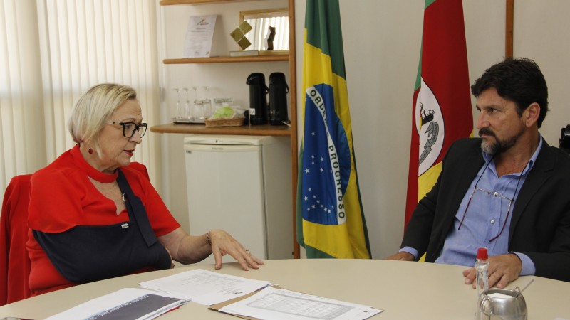 Secretária Arita Bergmann e prefeito de Alegrete, Márcio Amaral, dialogam em mesa de reunião.