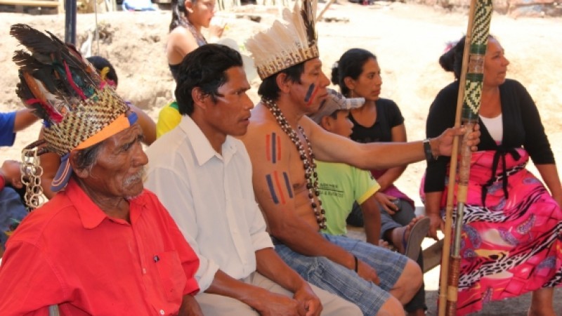 Imagem mostra um grupo de indígenas sentados. 