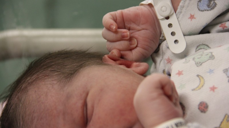 Foto mostra recém-nascido num leito de hospital.