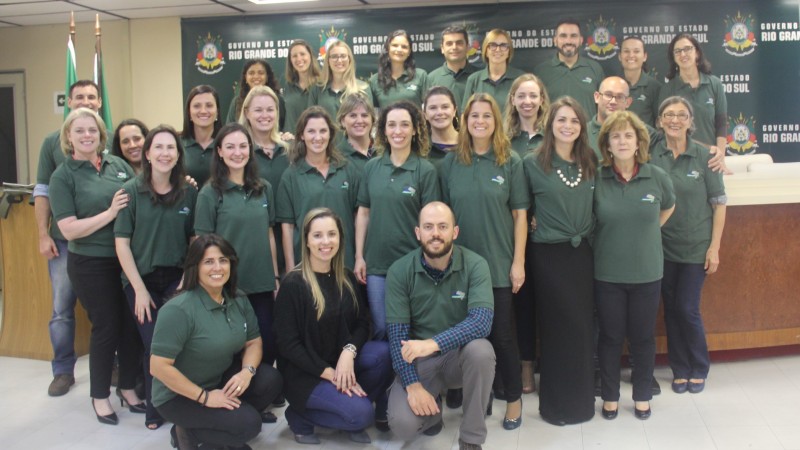 Participantes do treinamento posam para a foto. De pé ou agachados, todos vestem uma camiseta verde.