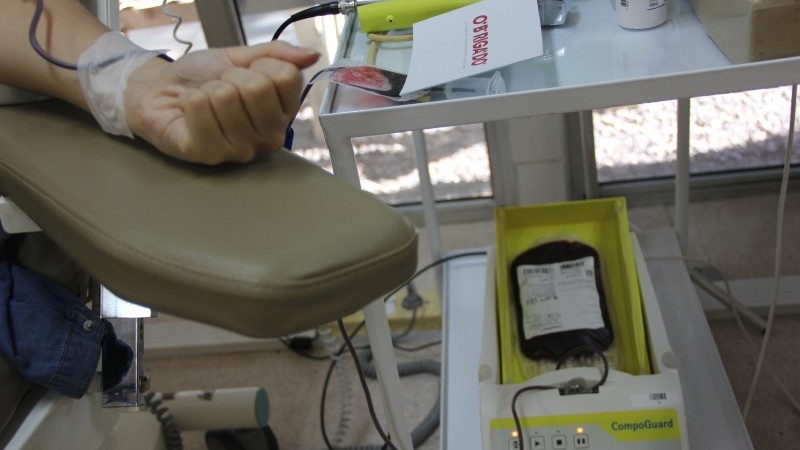 A imagem mostra um braço doando sangue, além de aparelhos.  