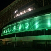 Arena do Grêmio iluminada de verde à noite.