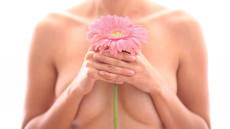 foto de uma mulher cobrindo os seios com uma flor,s em mostrar o rosto